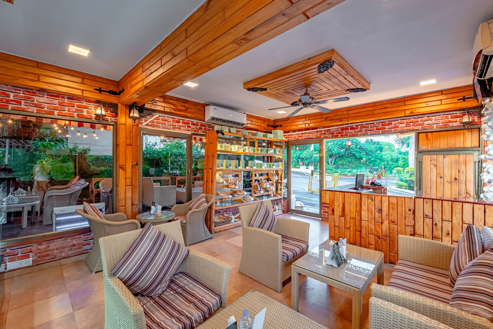 Teak-panelled indoor seating with striped armchairs and a wide window onto the garden